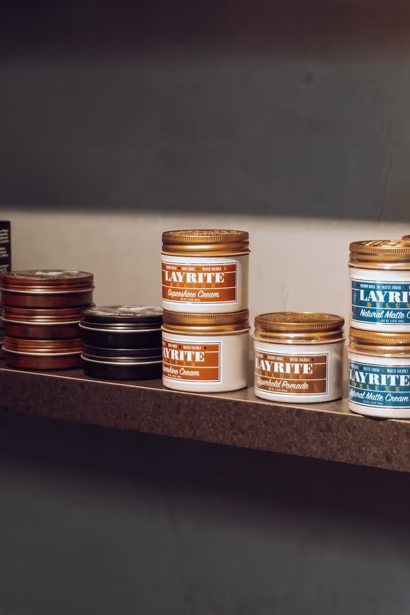 A shelf of premium men's hair care products displayed against a clean, modern wall.
