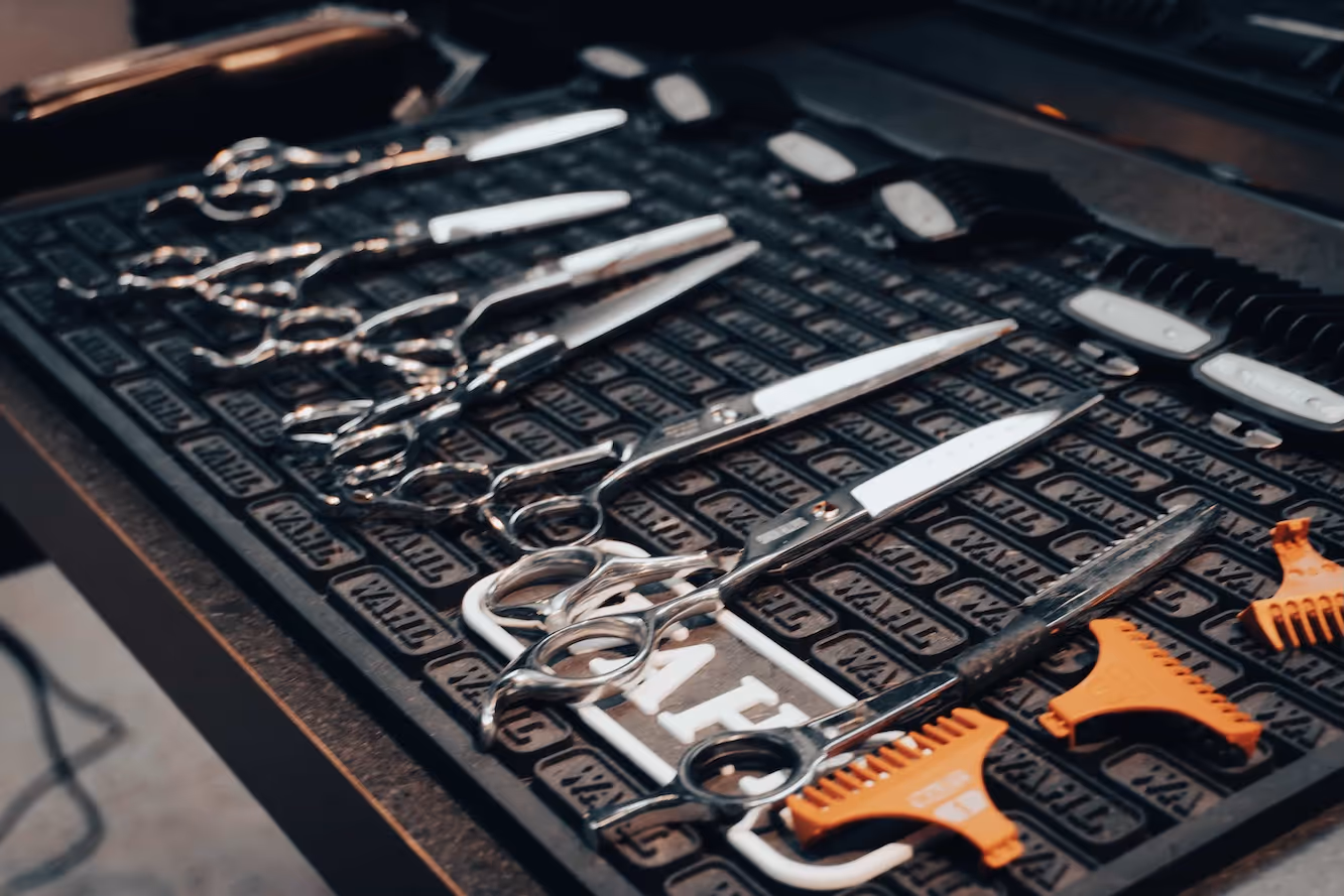A close-up of professional barbering tools, including scissors, combs, and clippers.