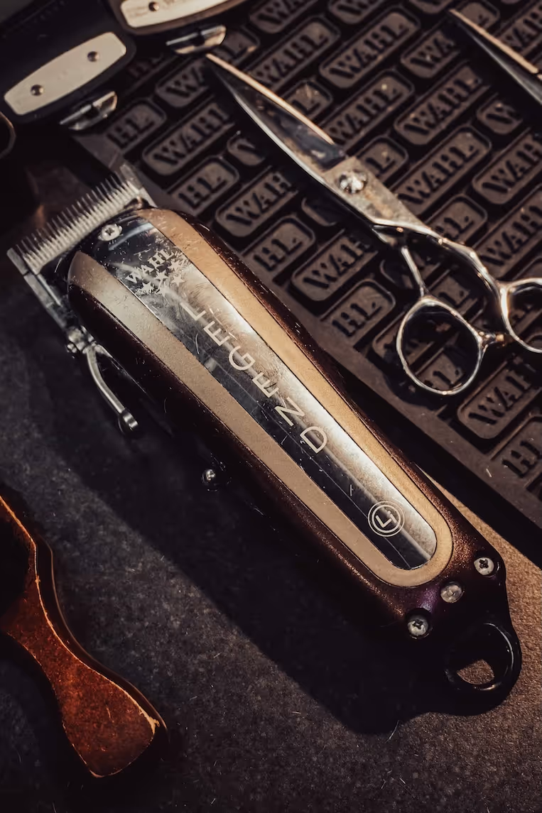 A close-up of a professional barber's razor and electric shaver on the counter.
