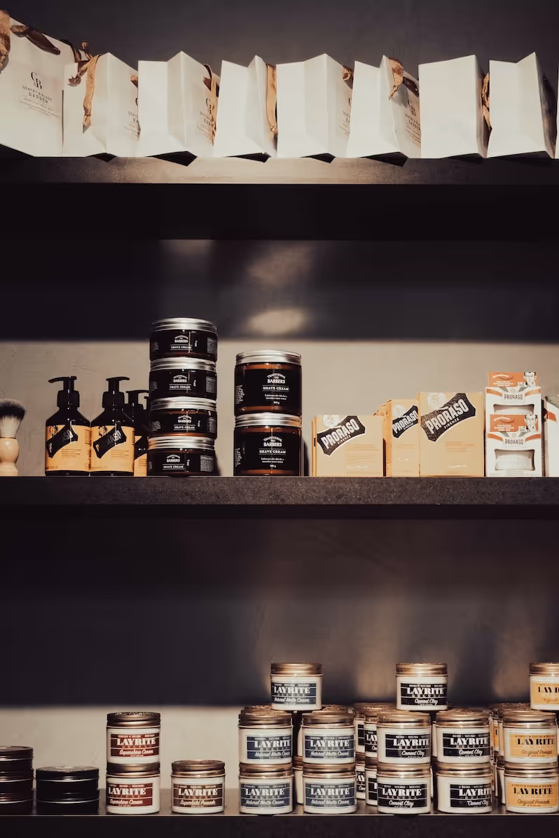 Premium men's hair and grooming products displayed on a wooden shelf in the barbershop.